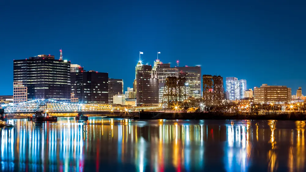 Newark, New Jersey skyline illuminated at night and reflected across the Passaic River