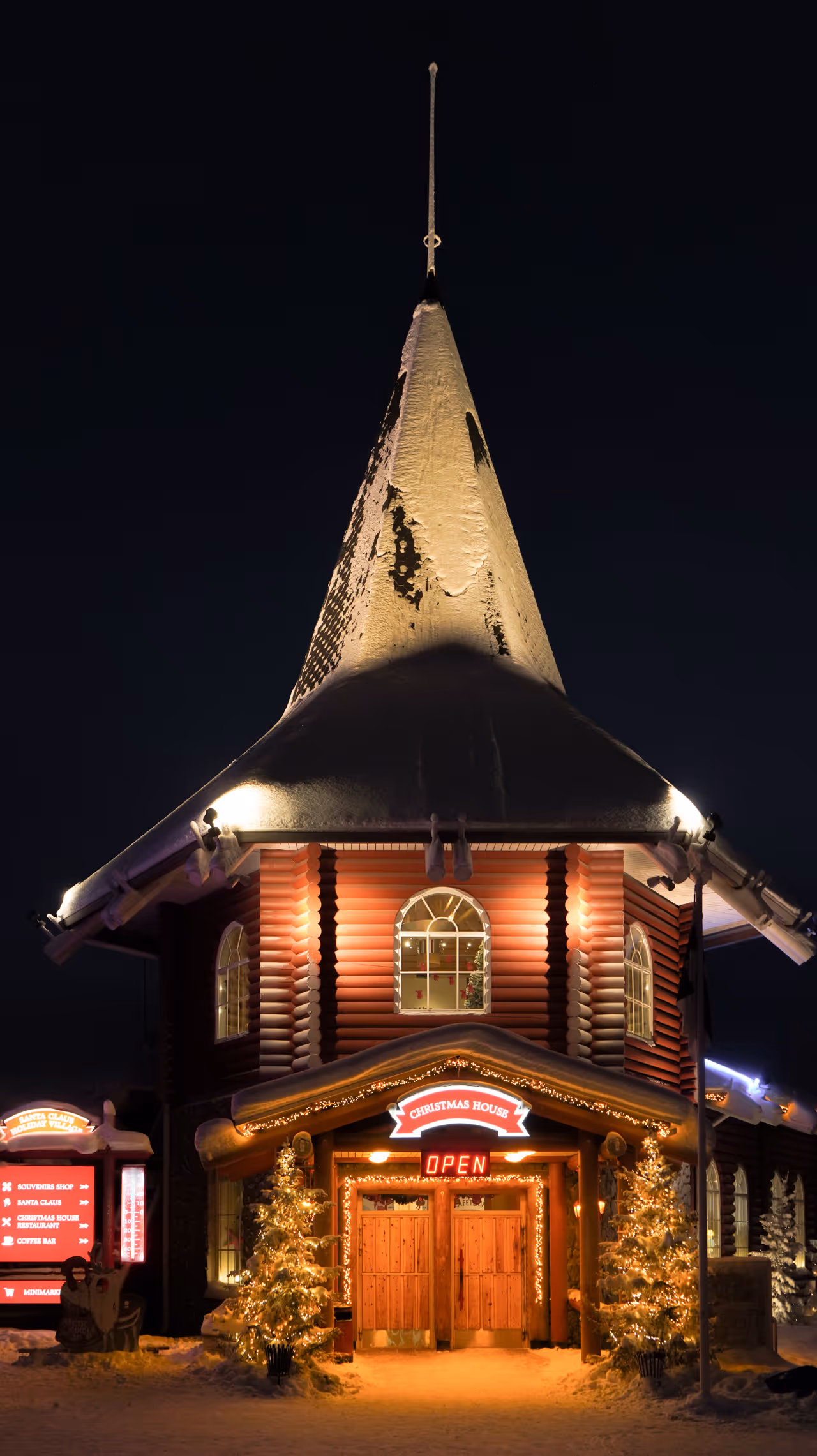 Snow-covered Christmas House with lights and a glowing "OPEN" sign at night.