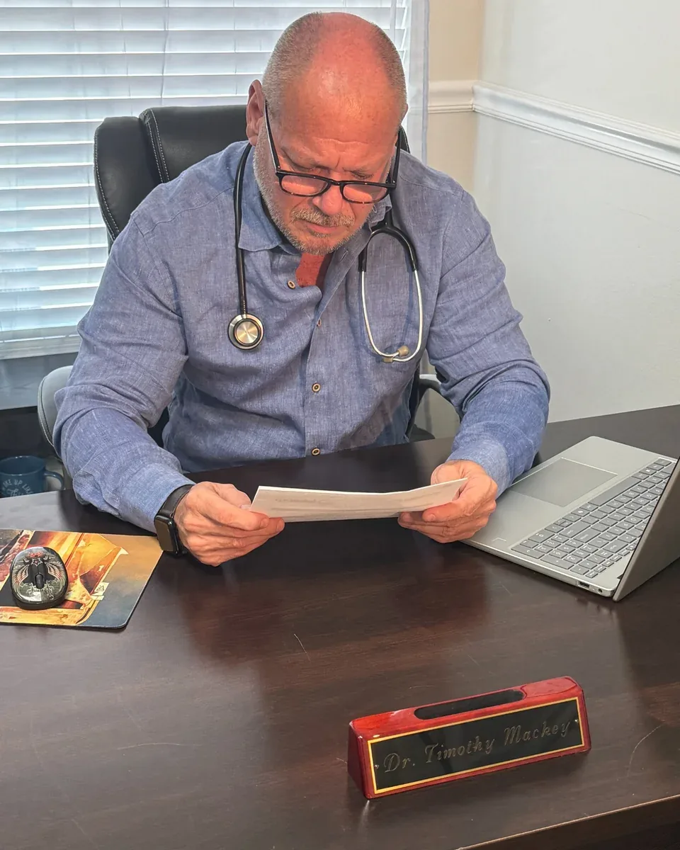 Dr. Timothy W. Mackey, D.O. reviewing a patient's laboratory results at his desk in the NovaGenix office in Jupiter, Florida