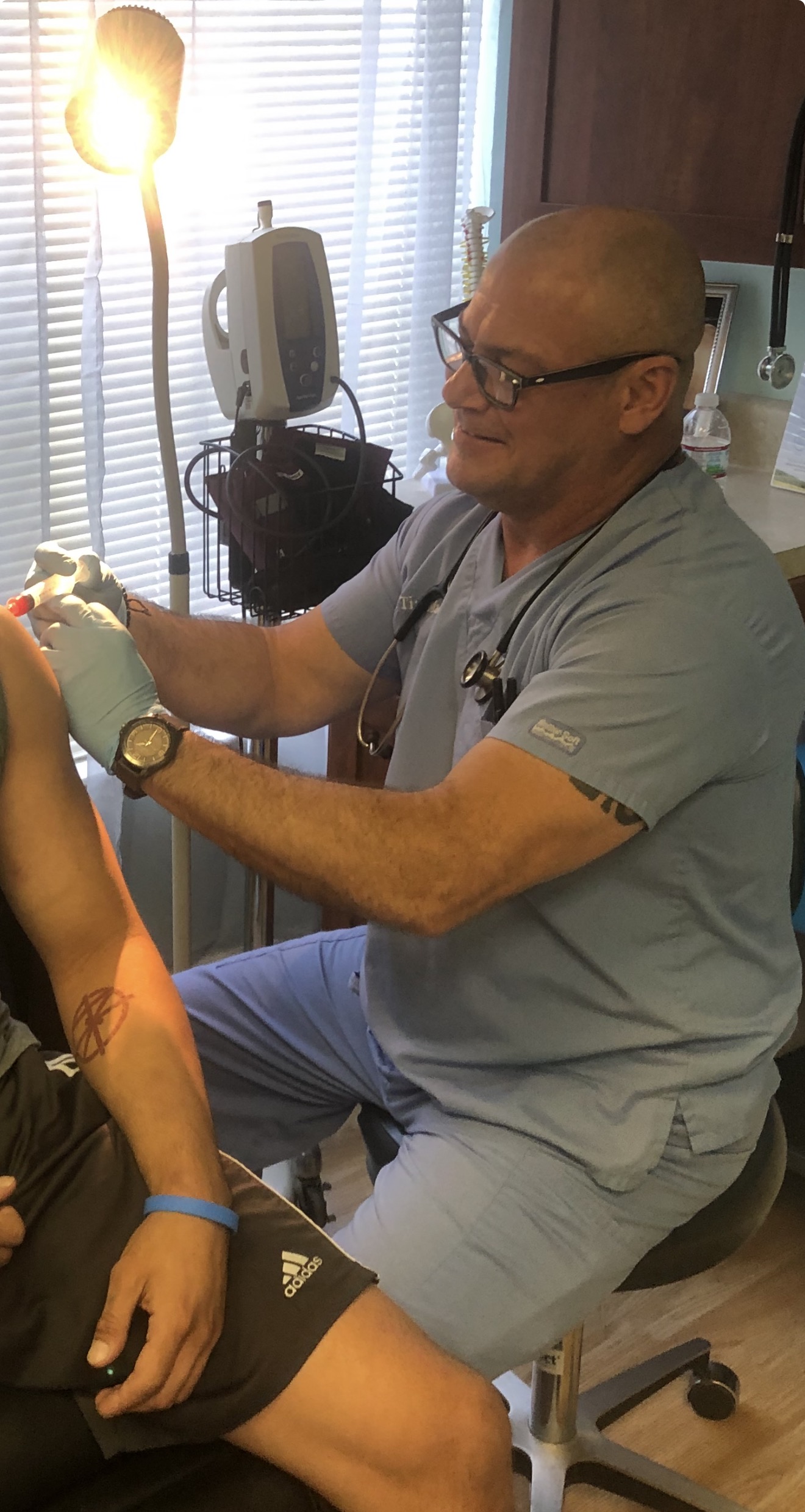 Dr. Timothy Mackey examining a patient's knee at NovaGenix in Jupiter