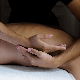 Deux mains qui massent le côté d'une personne allongée.