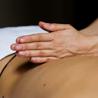 Deux mains qui massent le dos d'une personne allongée