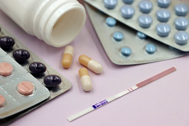 Pregnancy test and pills on the pink background