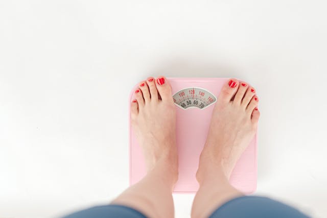 Woman's Legs Standing on a Pink Scale
