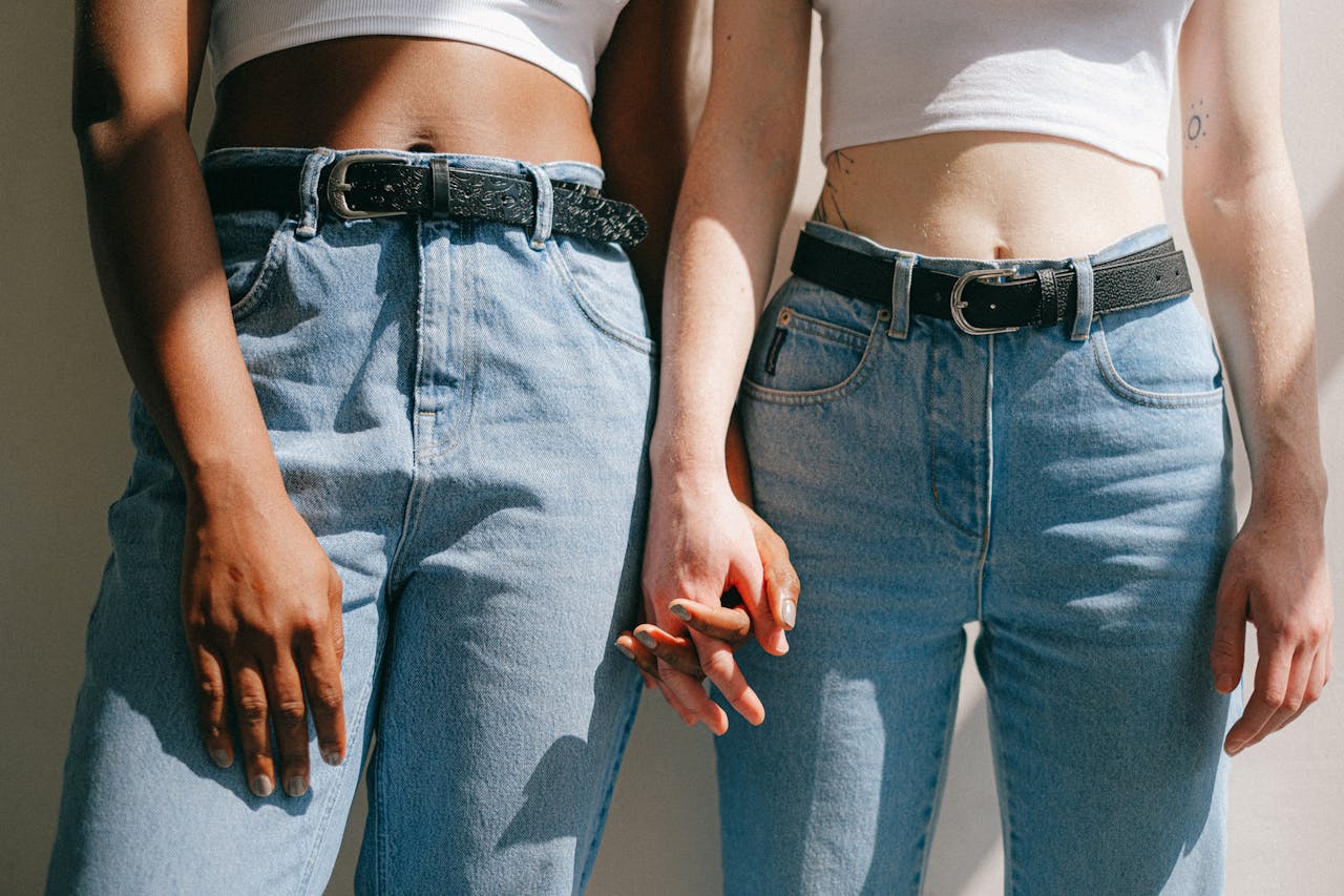Two Women in Blue Jeans and Cropped White Tops Standing Holding Hands