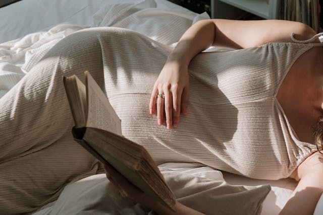 A Pregnant Woman Reading a Book while Lying Down
