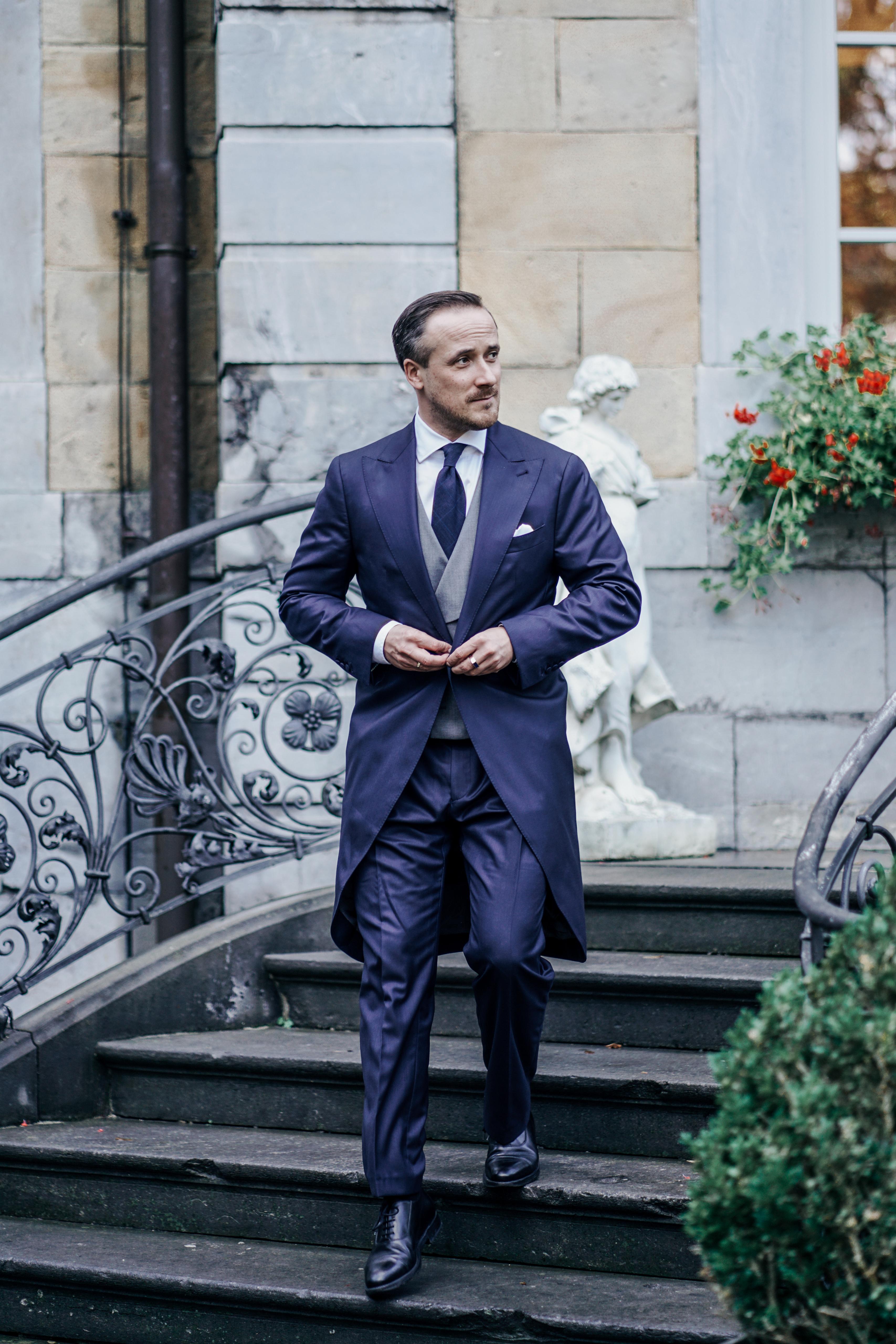 Sohn von CDU-Politiker Armin Laschet, Johannes Laschet, hier zu sehen an seinem Hochzeitstag. Er trägt einen klasischen dunkelblauen Cut mit grauer Weste als Hochzeitsanzug. Dazu eine Dunkelblaue Krawatte.