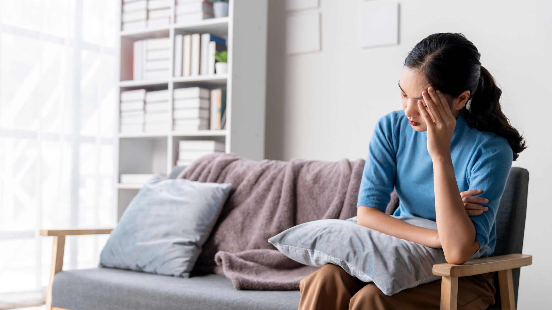 Woman on sofa experiencing a headache