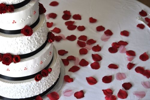 A wedding cake with roses around it.