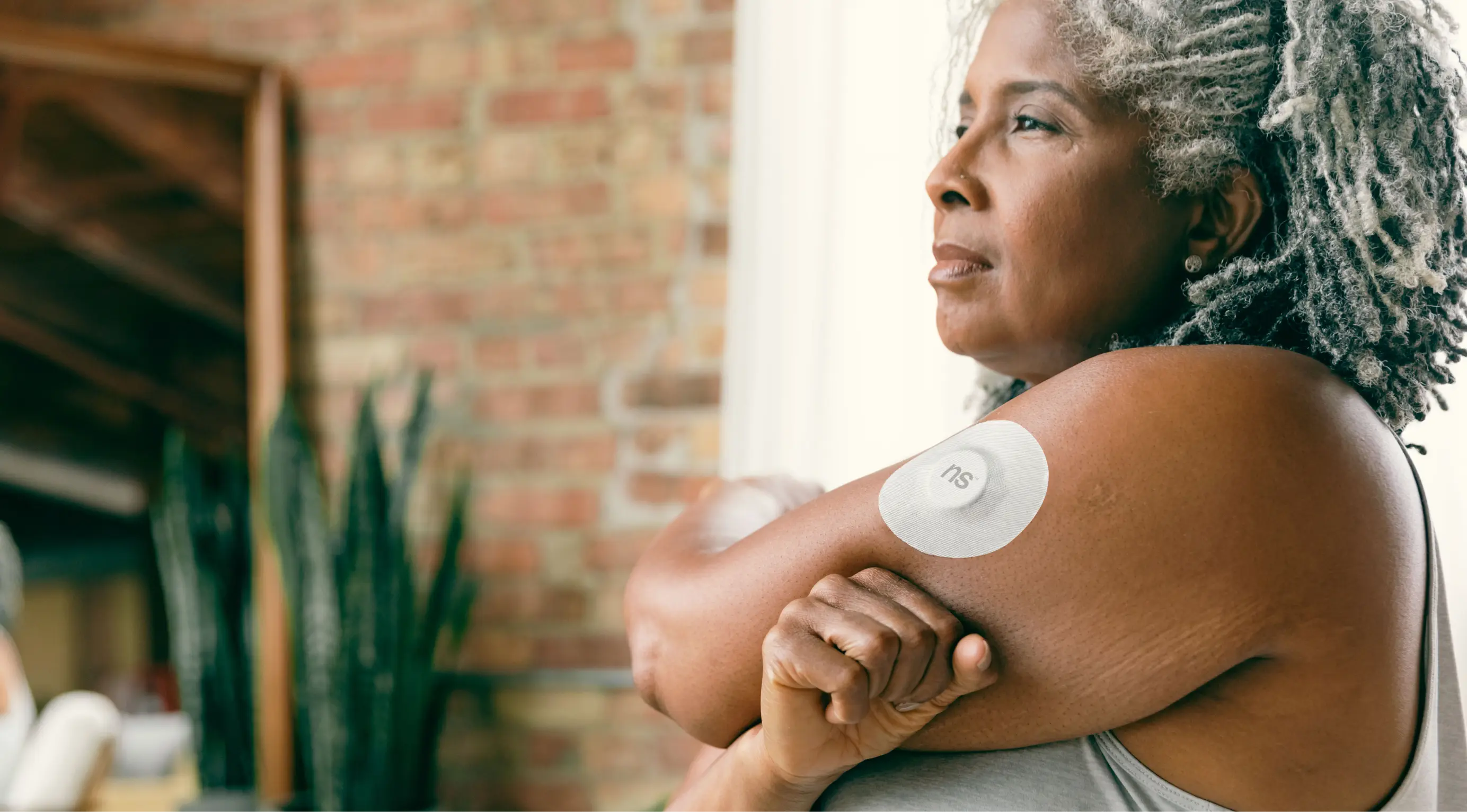 A woman stretches her left shoulder wearing Nutrisense CGM tracking device on her upper left hand available in nutrisense.io