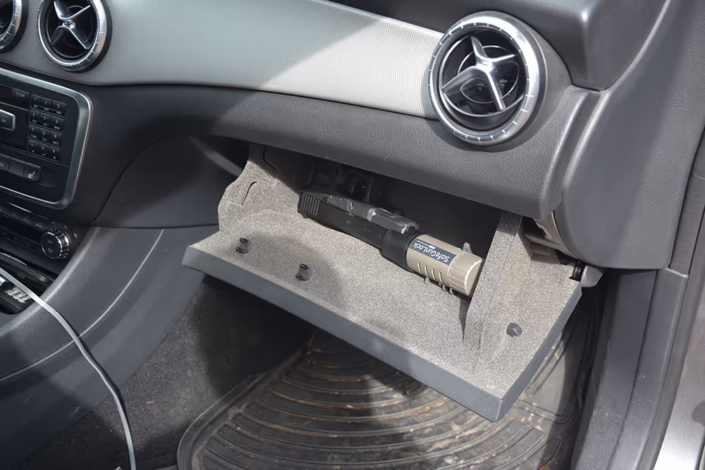 A handgun with SafeGunLock inside the dash of a car