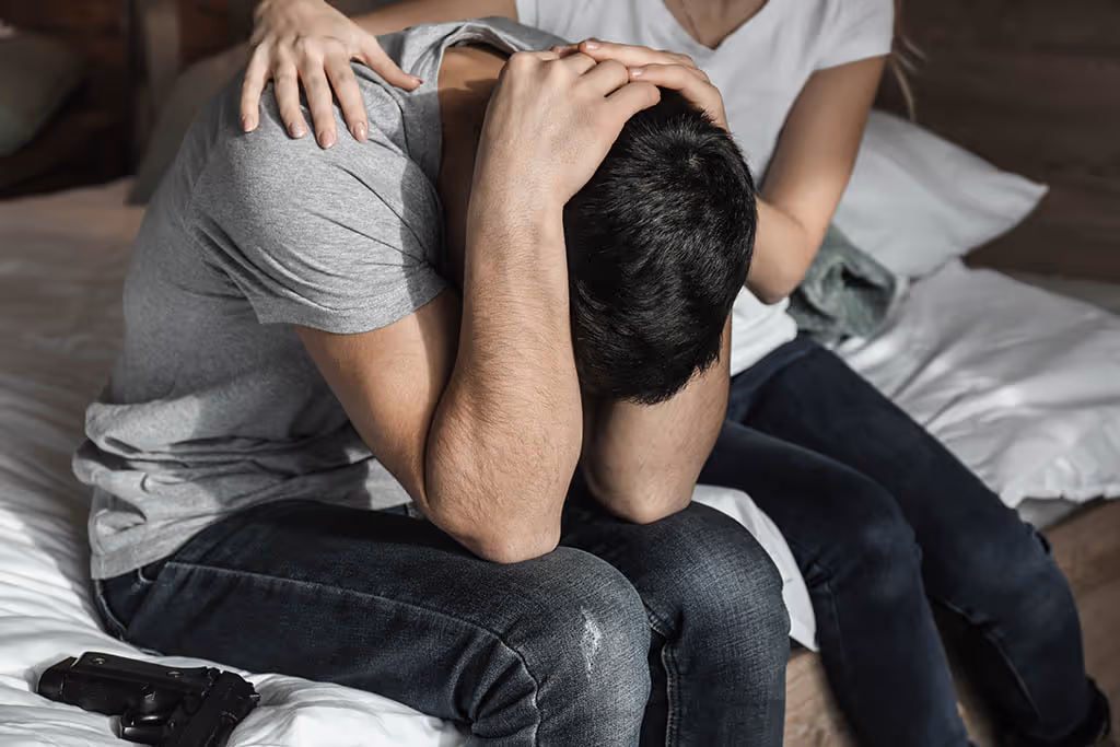 A mother consoling her suicidal son with a handgun by his side