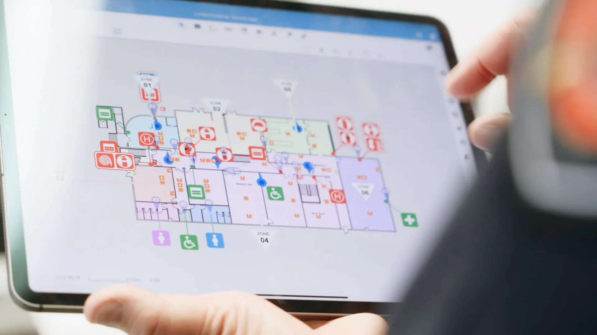 A person holding a tablet with a floor plan on it.