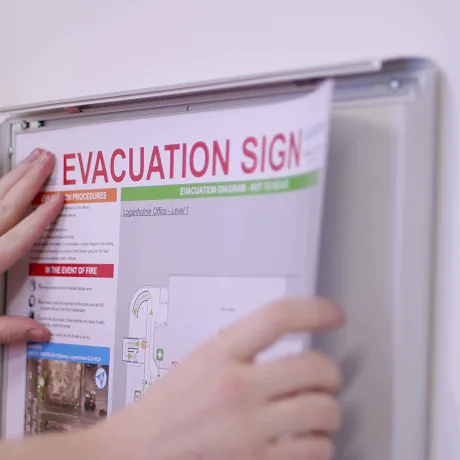 A person is placing an evacuation sign on a wall.