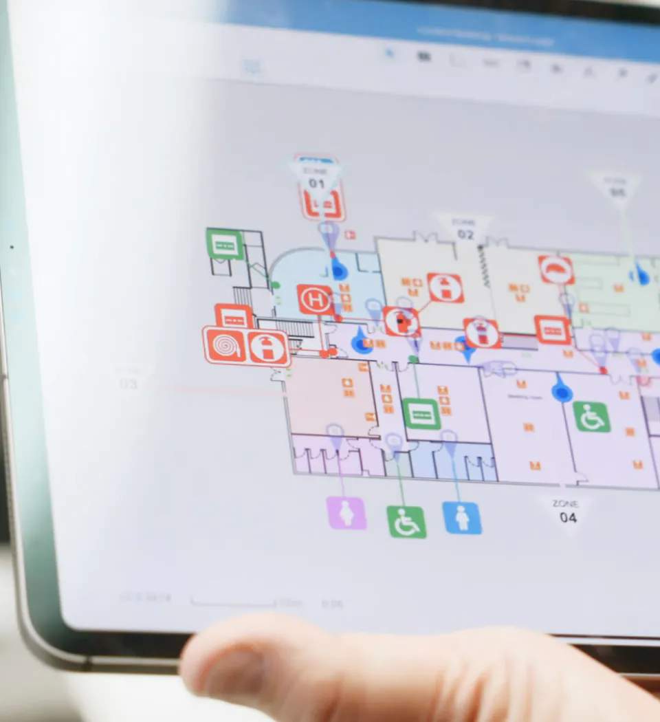 A person holding a tablet with a floor plan on it.