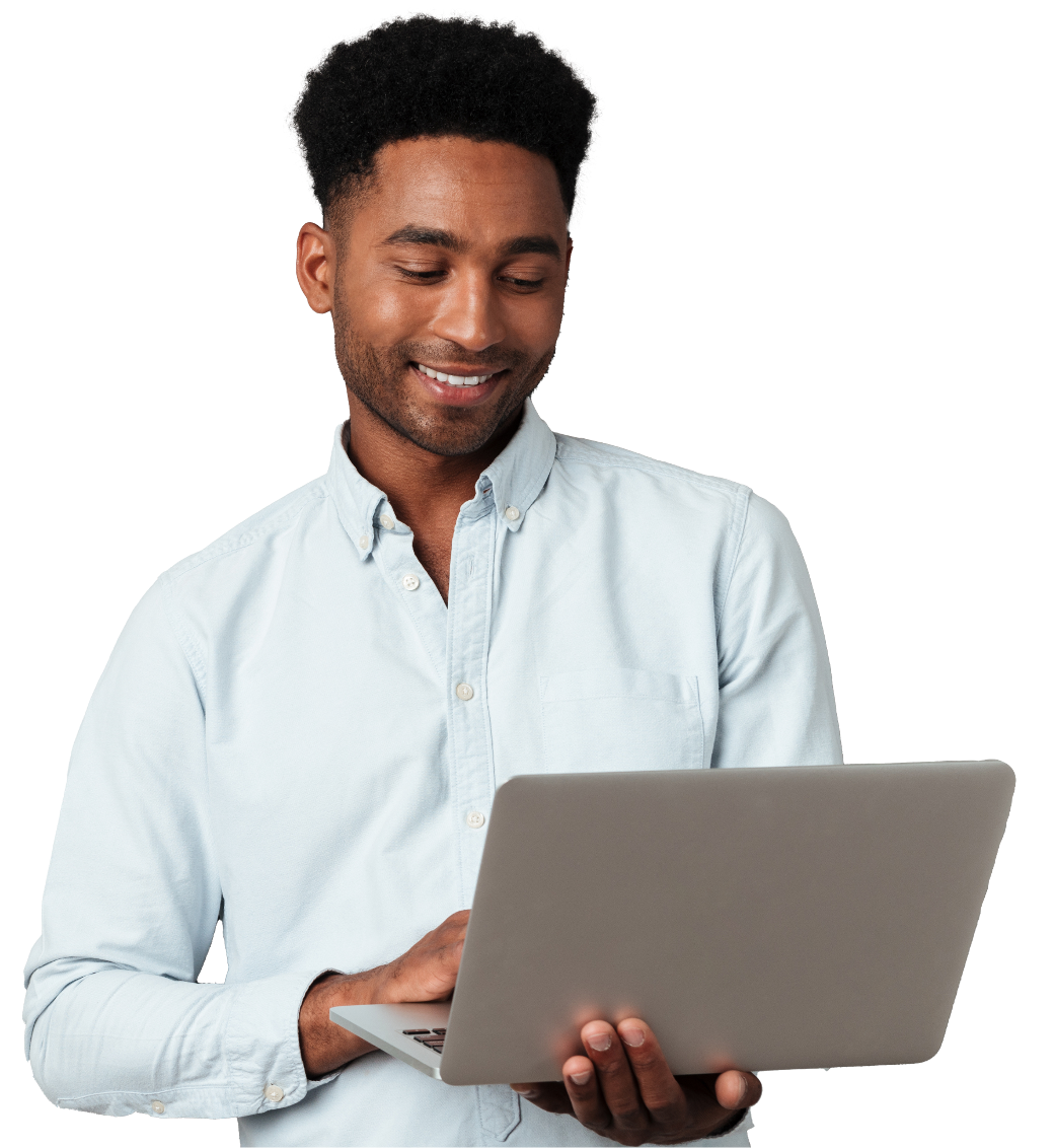 Smiling man in a light blue shirt holding and using a laptop, looking at its screen.