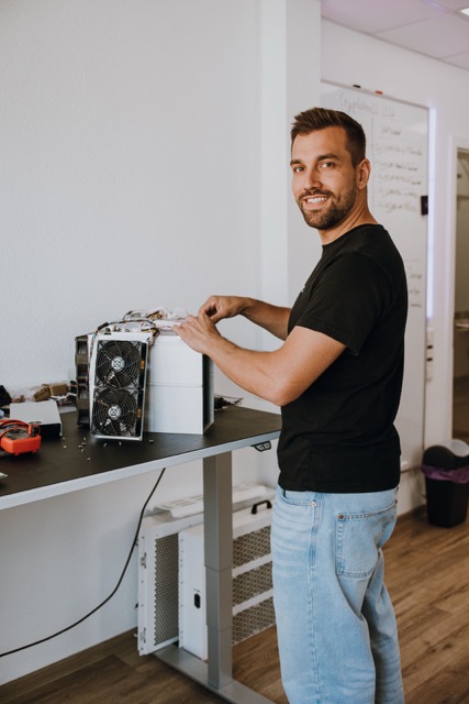 Cryptohall24 employee providing technical support on an ASIC miner - Cryptohall24
