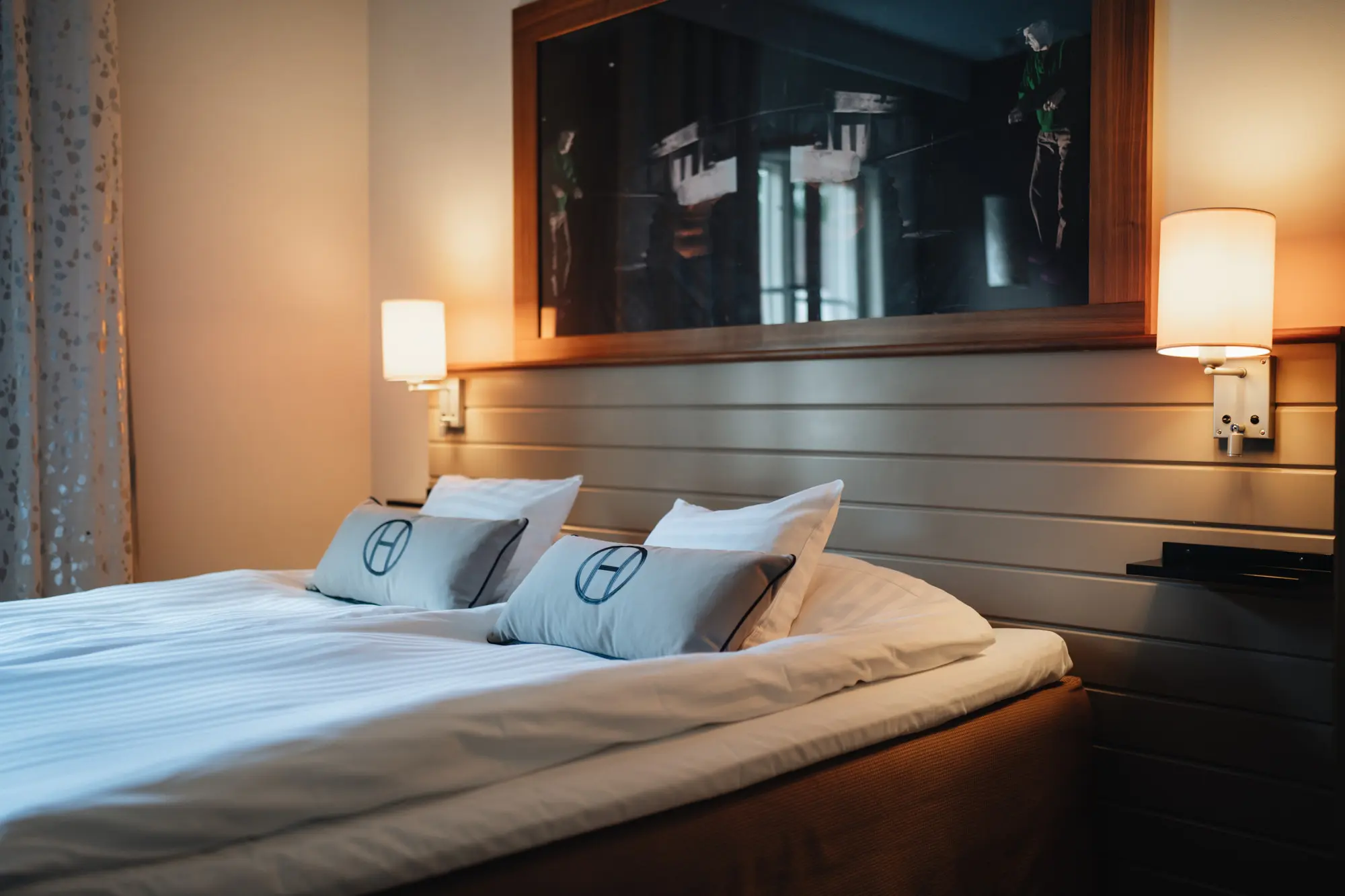 Hotellrum på Högbo Brukshotell med inbjudande bäddning och mjukt ljus.