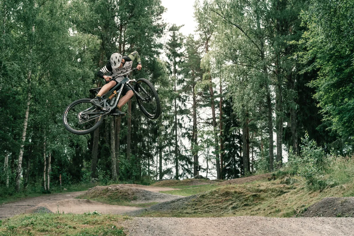 En man på mtb hoppar med cykeln i skogen.