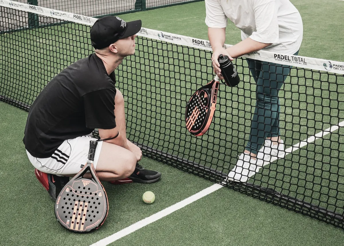 Två personer pratar på padelbanan