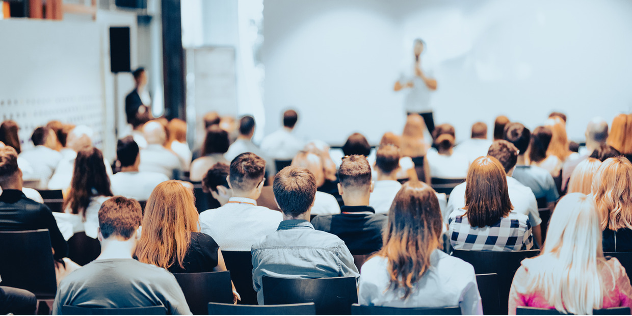 Audience seated and listening to a speaker presenting at a professional conference or training seminar