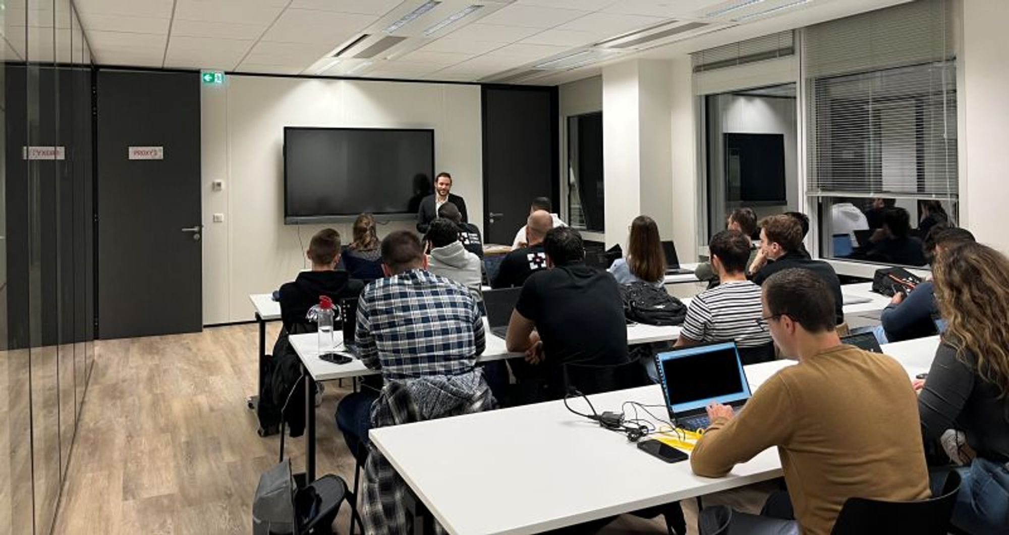 a group of people sitting at tables with laptops in front of them