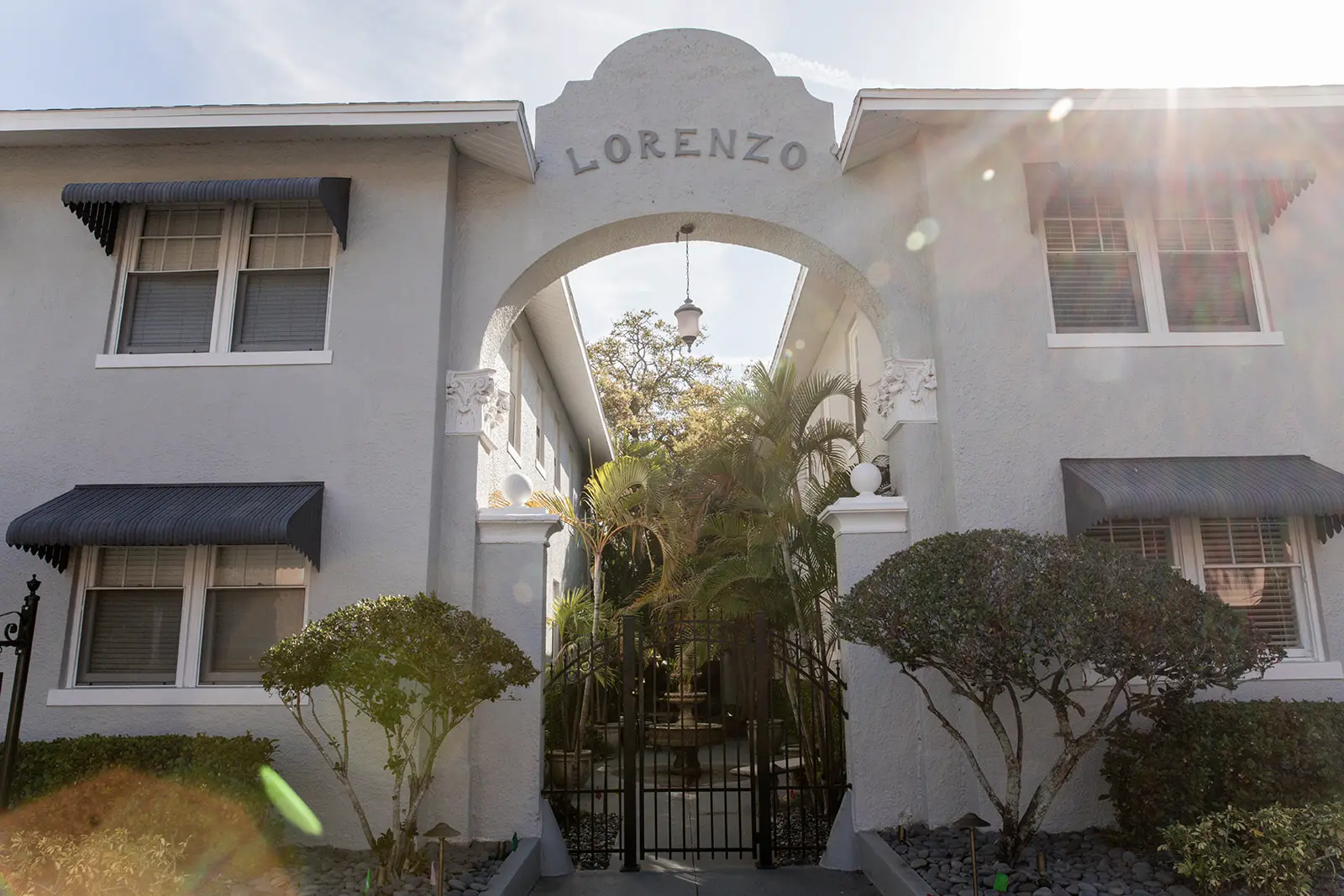 View of front facade of apartment building with with gated fountain courtyard with archy way stating "Lorenzo."