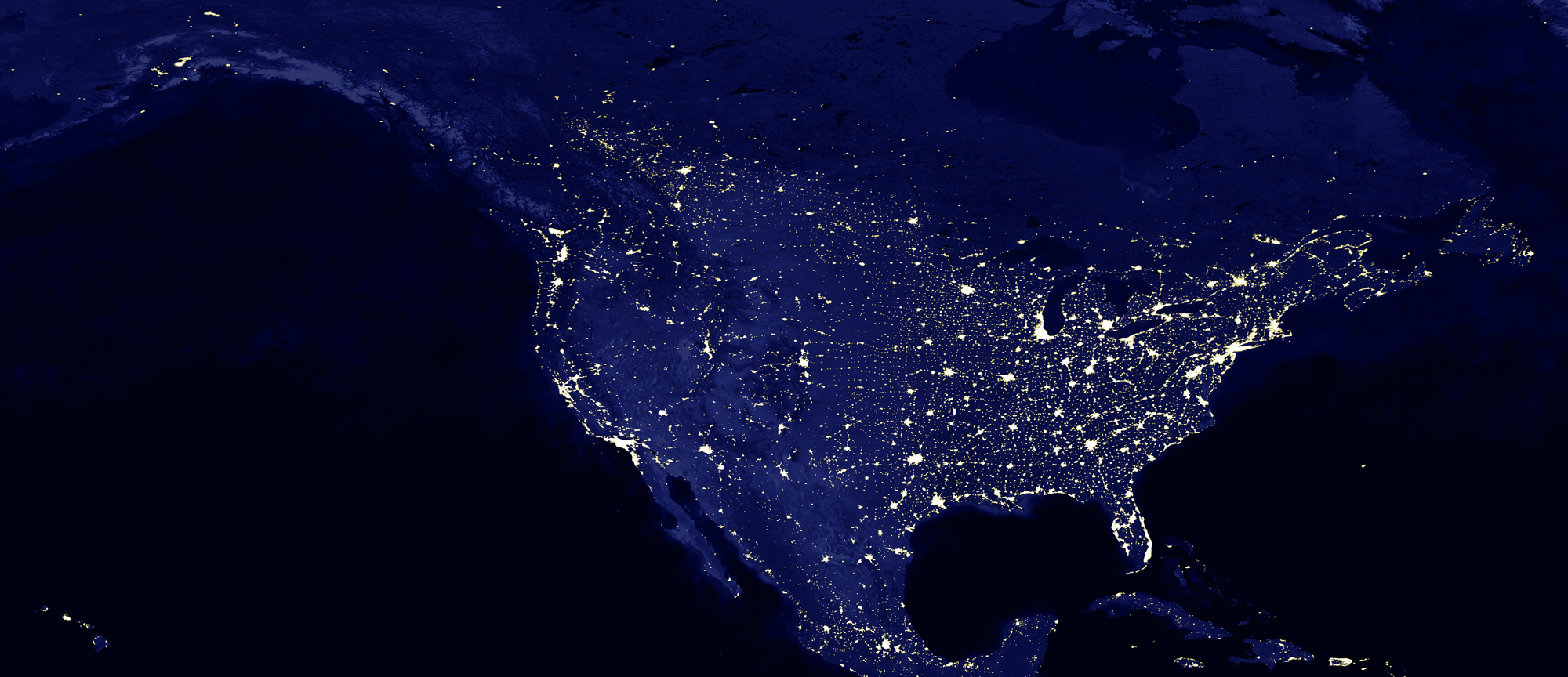 An electric vehicle driving down a highway with wind turbines in the background.