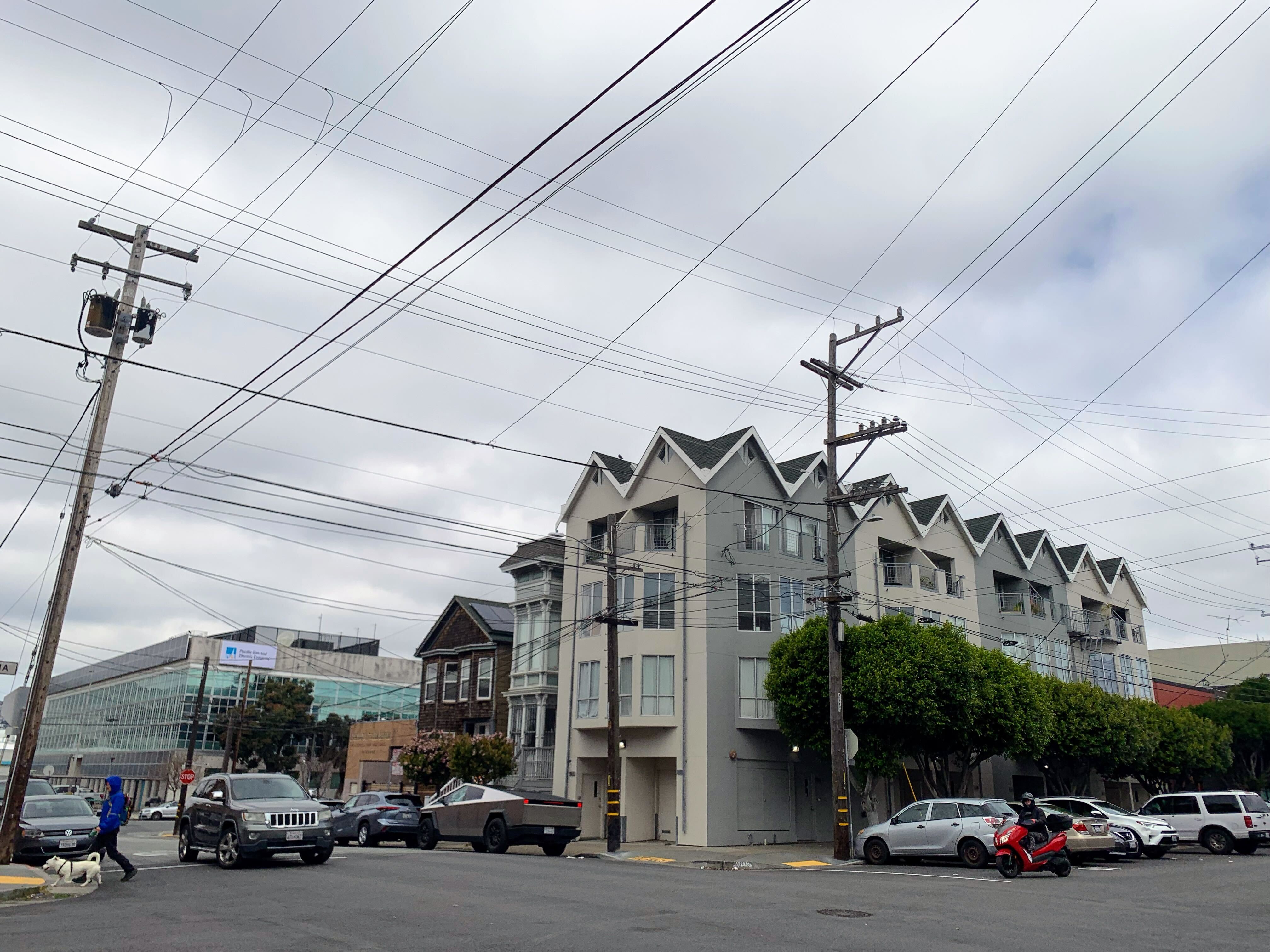 A residential street with distribution infrastructure and power lines running overhead.
