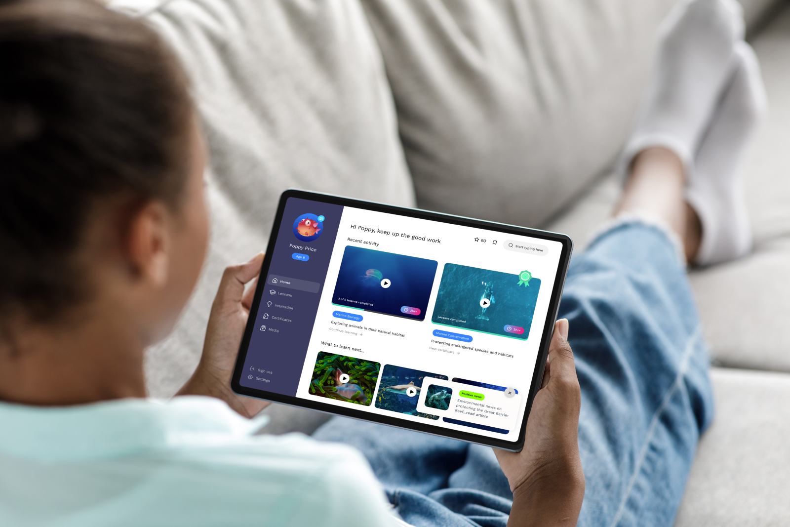 Person holding a tablet showing an educational app interface with marine zoology and conservation lessons.