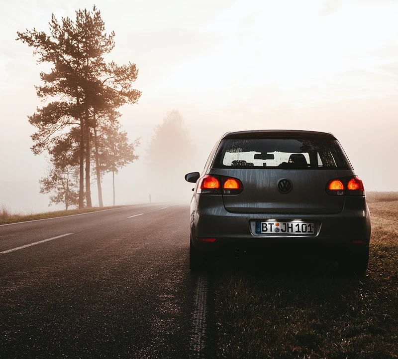 Silver VW Golf parked up at the side of a country road on a misty morning, with a line of trees on the opposite side of the road.