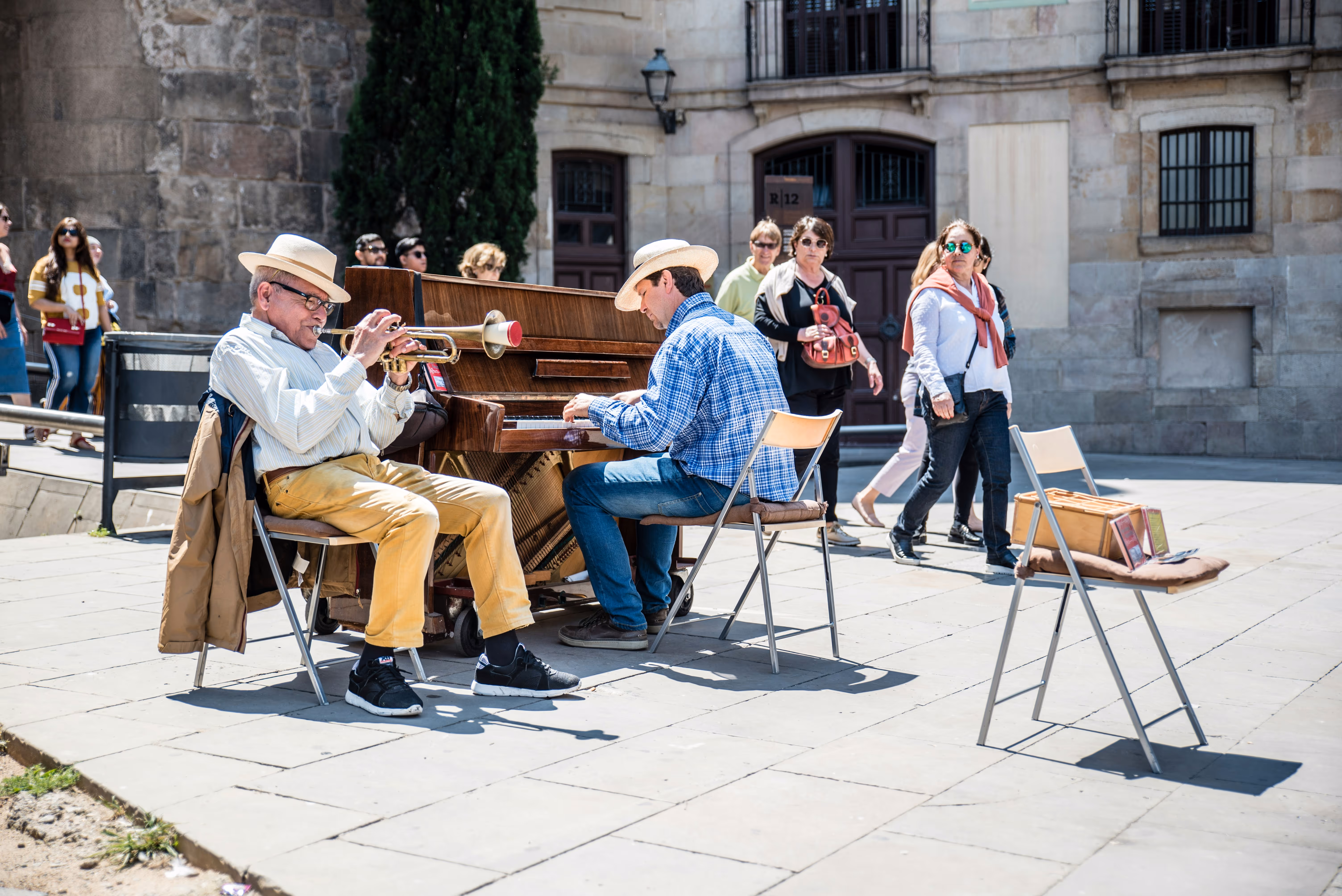 People playing instruments in rustic, European city square with people looking on