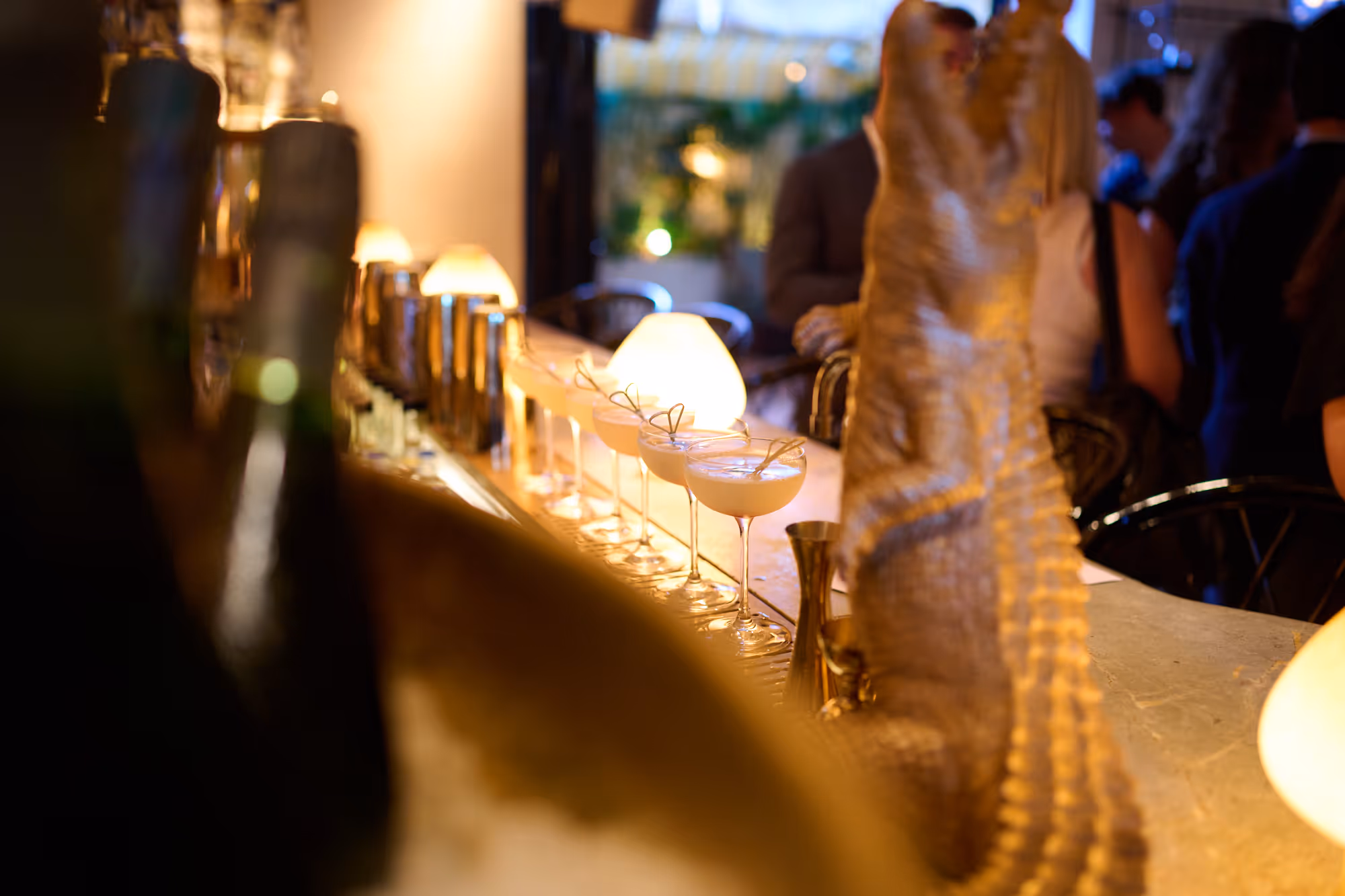 French 75 cocktails lined up elegantly on bar of Louie London with evening lighting