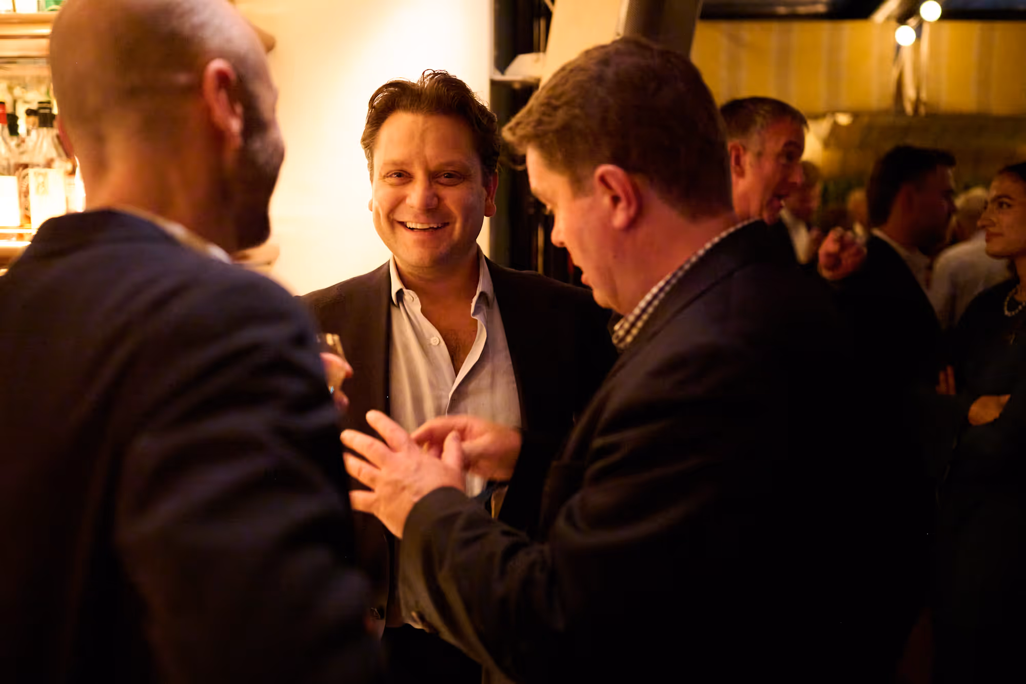 Three men laughing together in conversation.