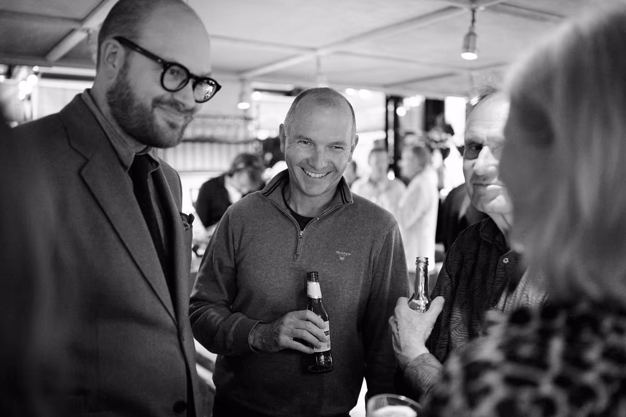 Two men laughing in conversation with another person, sepia tones
