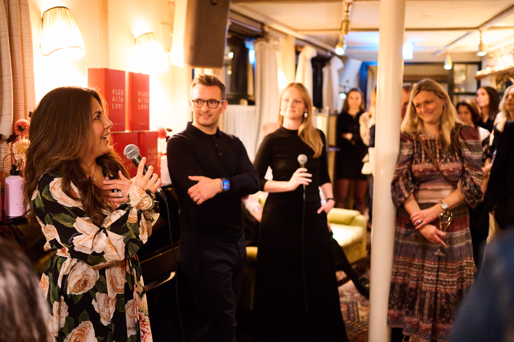 People smiling as woman speaks on the mic in luxury bar