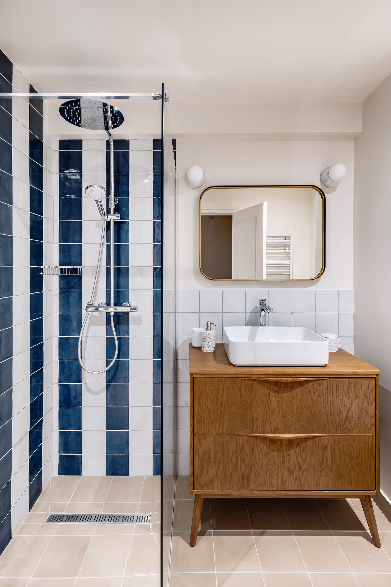 Shower with stiped blue and white tile and mid-century modern, wooden vanity unit 