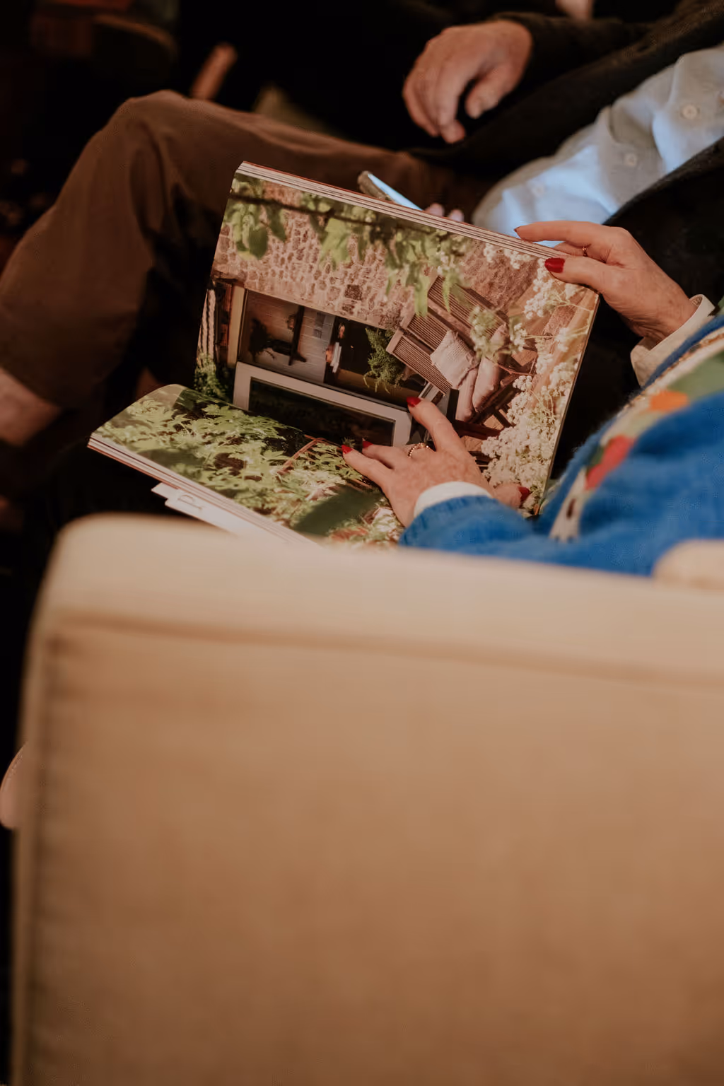 person holding open book with beautiful photography of a brick home exterior of patio area
