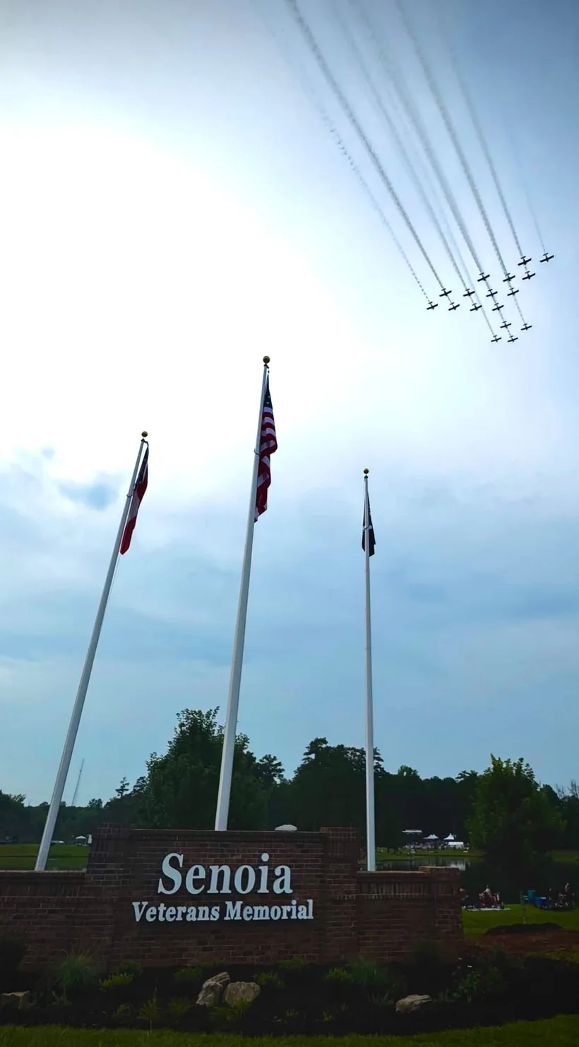 The United States, Georgia, and POW/MIA flags flying over the Senoia Veterans Memorial.