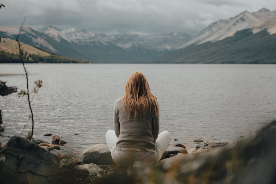 a woman sitting on a rock near a body of water