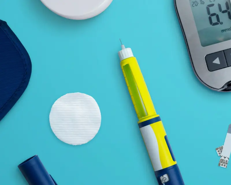 lose-up of a GLP-1 medication injection device alongside glucose monitor.
