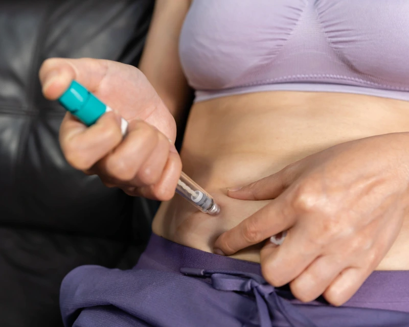 Patient self-administering an Ozempic injection in the stomach for weight loss treatment.