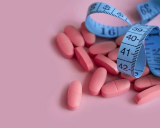 Weight loss pills next to a tape measure to represent potential weight loss from medication.