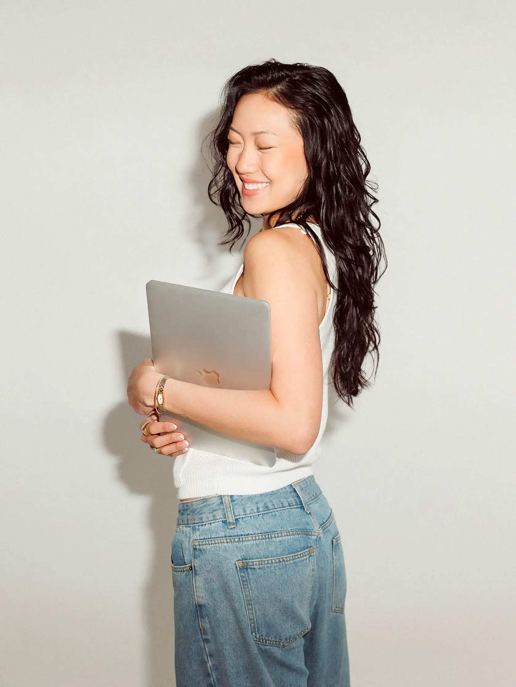 Founder Alyssa Nguyen holding laptop and smiling to the side