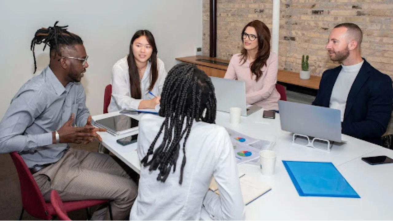 A group of business professionals in a meeting room having a discussion.