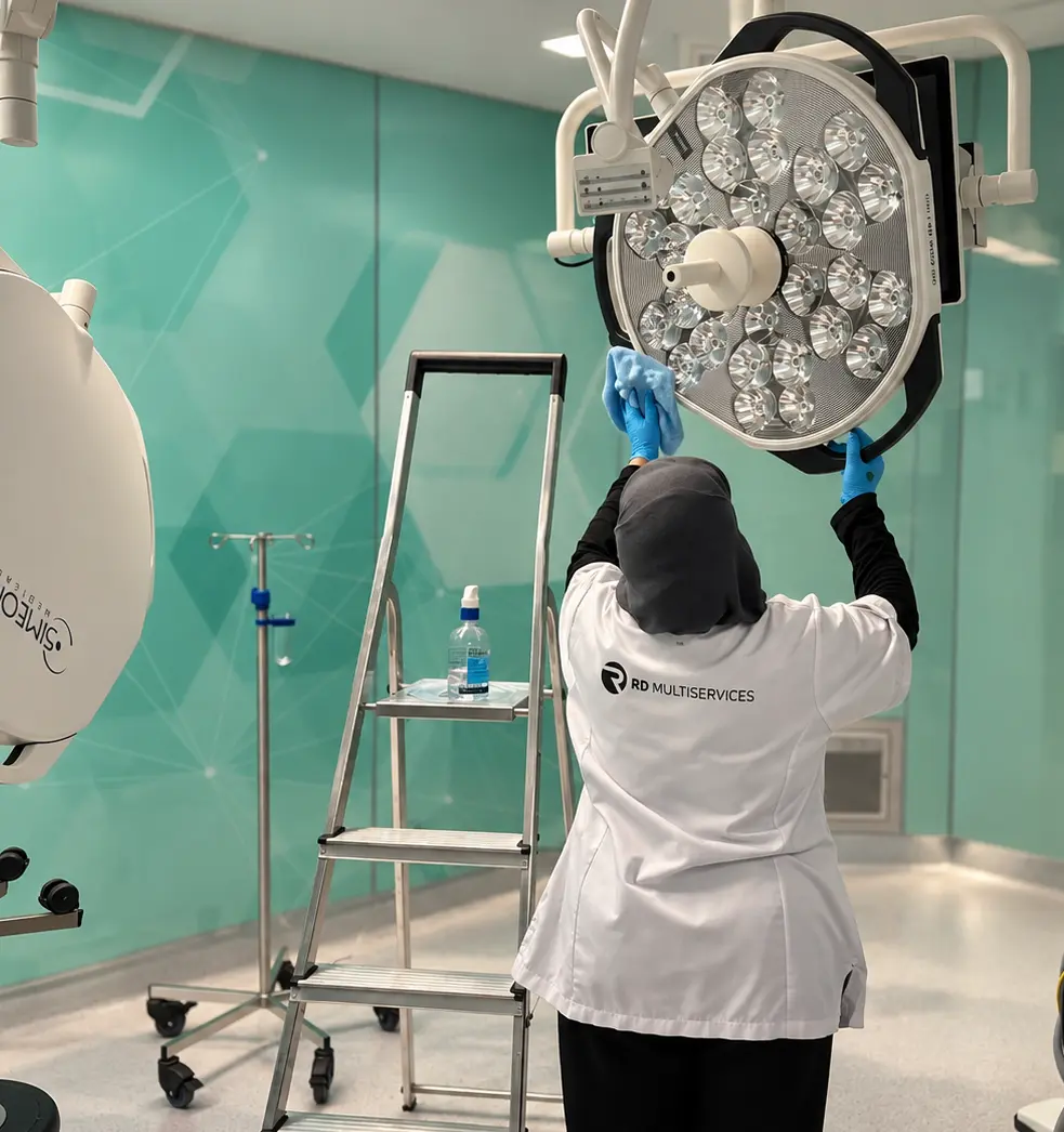 Schoonmaakster van RD Multiservices in wit uniform reinigt medische apparatuur in een zorginstelling