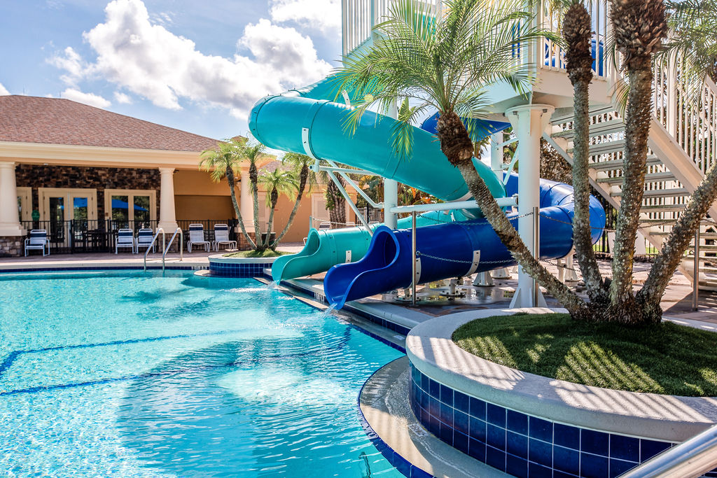Bright blue waterslides curving into the community pool at Live Oak Reserve