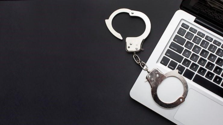Flat lay of handcuffs with laptop and copy space, blank stealing, online crime. 