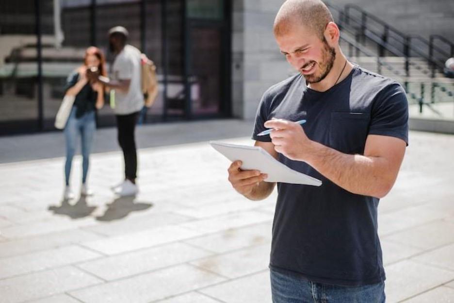 Man standing outside holding notepad grinning. Sanction checking.