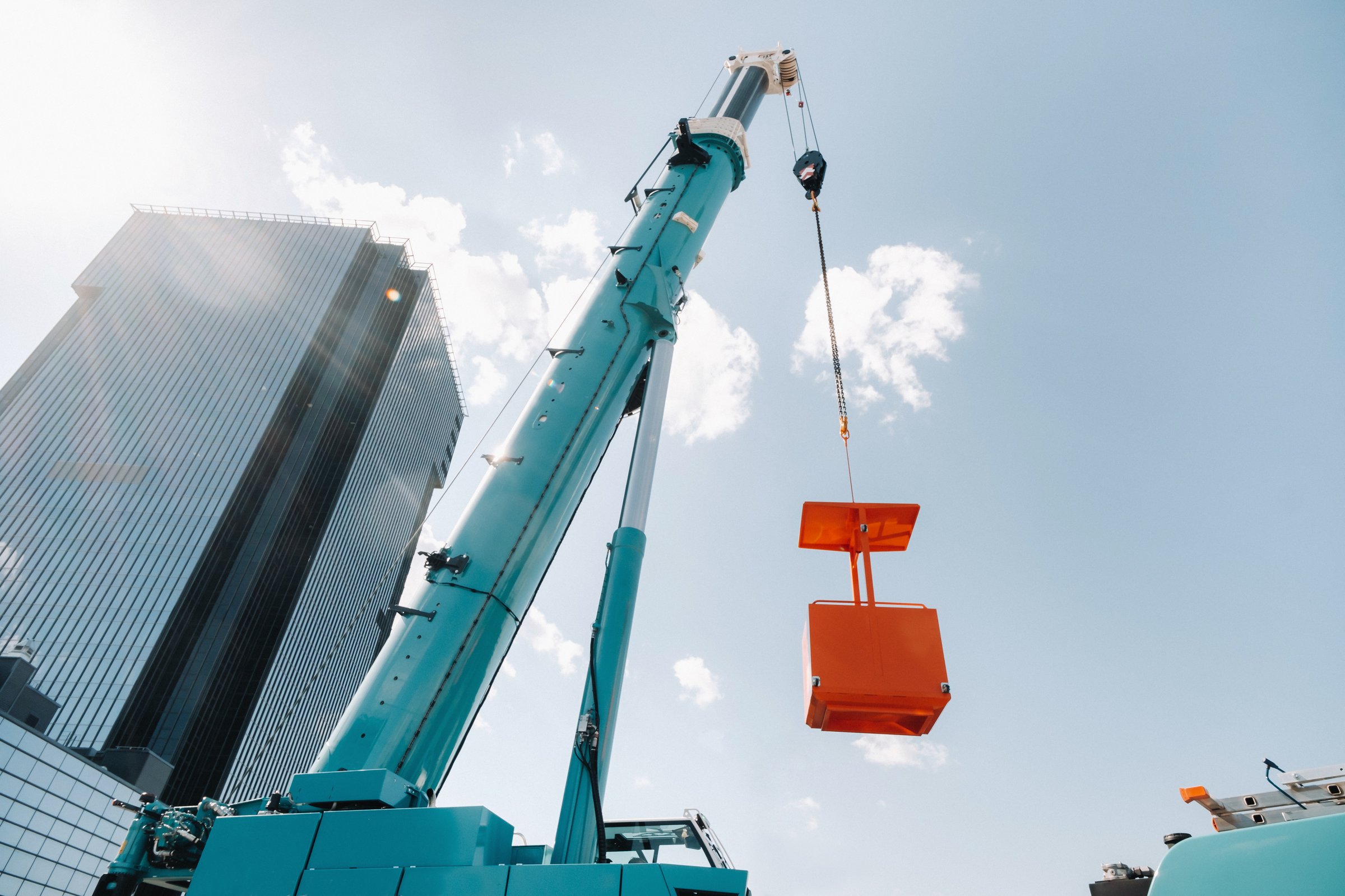Mobile crane lifting a load beside a modern commercial high-rise